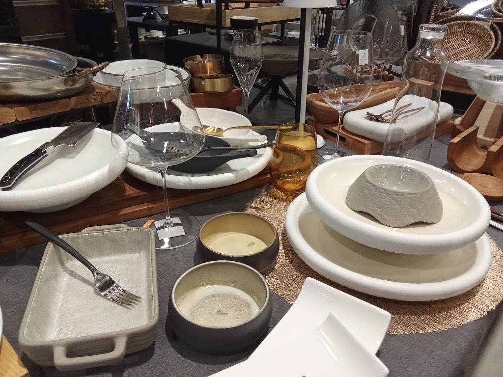 Mesa de exposición con platos de gres, copas, cuencos y cubertería